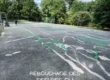 Fissures traversant un court de tennis en enrobé nécessitant un rebouchage avant rénovation