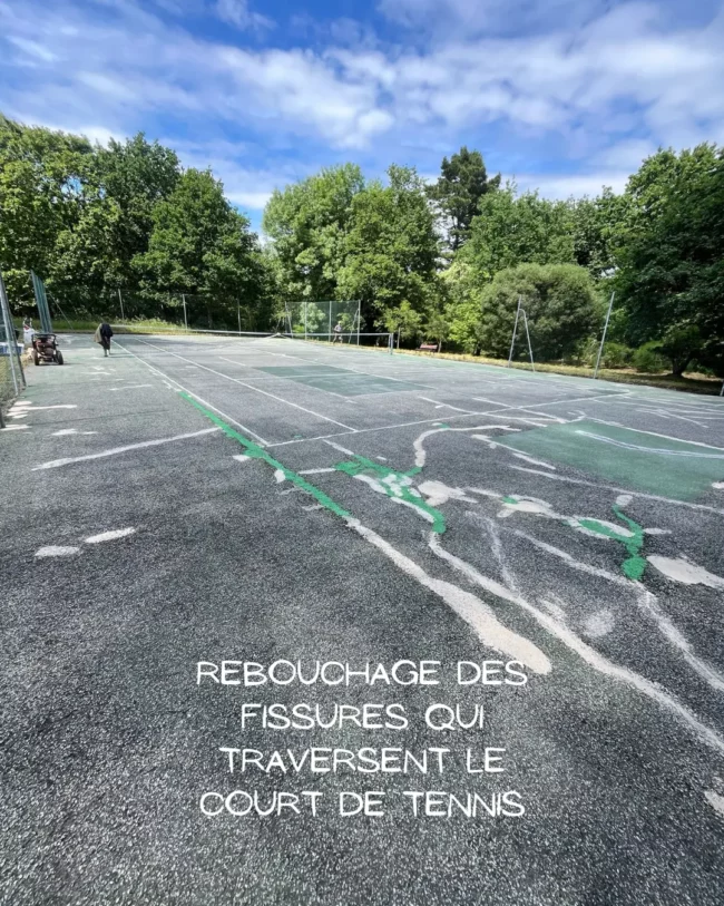Fissures traversant un court de tennis en enrobé nécessitant un rebouchage avant rénovation
