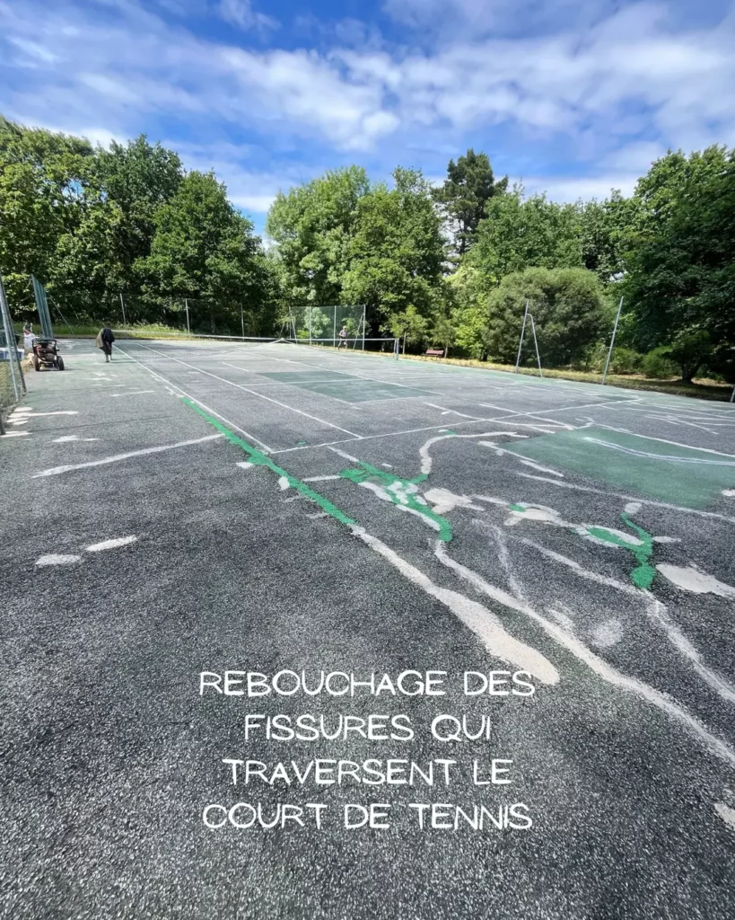 Fissures traversant un court de tennis en enrobé nécessitant un rebouchage avant rénovation
